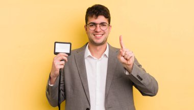 Genç yakışıklı adam gülümsüyor ve arkadaş canlısı görünüyor, bir numarayı gösteriyor. VIP geçiş konsepti