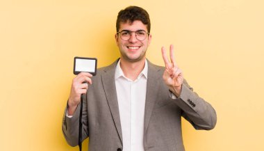 Genç yakışıklı adam gülümsüyor ve arkadaş canlısı görünüyor, iki numarayı gösteriyor. VIP geçiş konsepti