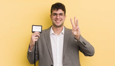 Genç yakışıklı adam gülümsüyor ve arkadaş canlısı görünüyor, üç numarayı gösteriyor. VIP geçiş konsepti