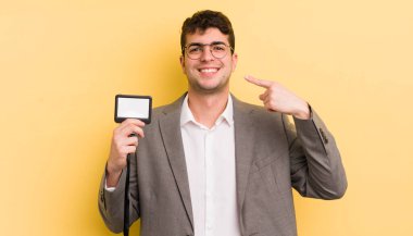 Genç ve yakışıklı bir adam kendi gülüşünü işaret ederek kendine güvenerek gülümsüyor. VIP geçiş konsepti