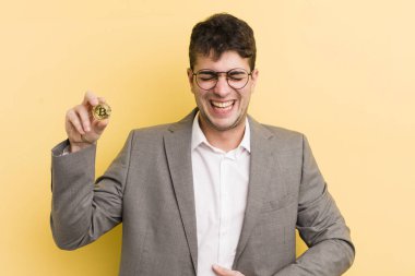 Genç yakışıklı bir adam komik bir şakaya yüksek sesle gülüyor. Bitcoin konsepti