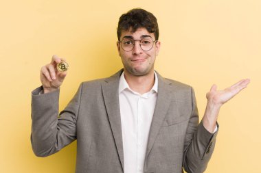 Genç yakışıklı adam şaşkın, şaşkın ve şüpheci hissediyor. Bitcoin konsepti