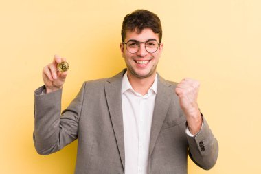 Genç yakışıklı adam şok olmuş hissediyor, gülüyor ve başarıyı kutluyor. Bitcoin konsepti