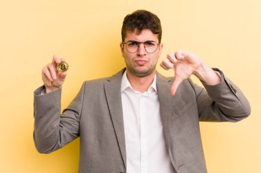 Genç ve yakışıklı bir adam kendini kötü hissediyor, baş parmağını kaldırıyor. Bitcoin konsepti