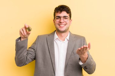 Genç ve yakışıklı bir adam arkadaşça gülümsüyor ve bir konsept sunuyor. Bitcoin konsepti