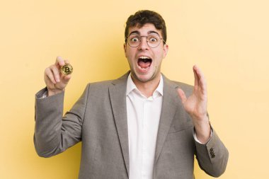 Genç yakışıklı adam kendini mutlu hissediyor ve inanılmaz bir şeye hayret ediyor. Bitcoin konsepti