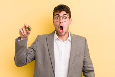Genç ve yakışıklı bir adam çok şaşırmış ya da şaşkın görünüyor. Bitcoin konsepti