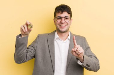 Genç yakışıklı adam gururla gülümsüyor ve kendinden emin bir numara oluyor. Bitcoin konsepti