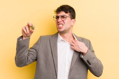 Genç ve yakışıklı adam stresli, endişeli, yorgun ve hayal kırıklığına uğramış hissediyor. Bitcoin konsepti