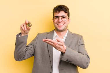 Genç yakışıklı adam neşeyle gülümsüyor, mutlu hissediyor ve bir konsept gösteriyor. Bitcoin konsepti