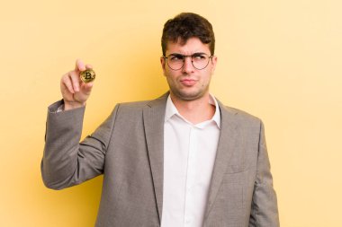 Genç ve yakışıklı bir adam üzgün, üzgün ya da kızgın hissediyor ve yan tarafa bakıyor. Bitcoin konsepti