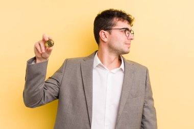 Profilde genç yakışıklı bir adam hayal kuruyor, hayal kuruyor ya da hayal kuruyor. Bitcoin konsepti