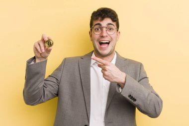 Genç yakışıklı adam heyecanlı ve şaşırmış görünüyor. Bitcoin konsepti