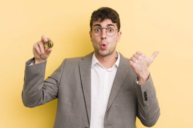 İnanamadığı için şaşırmış genç ve yakışıklı bir adam. Bitcoin konsepti
