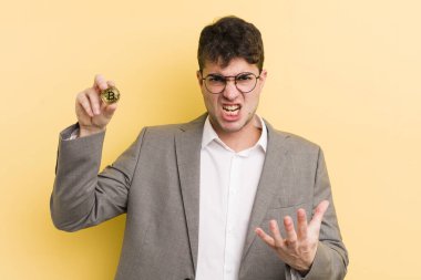 Genç ve yakışıklı bir adam sinirli, sinirli ve sinirli görünüyor. Bitcoin konsepti