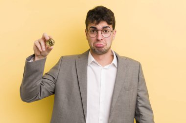 Genç ve yakışıklı bir adam üzgün ve mızmızlanıyor. Mutsuz bir bakışı var ve ağlıyor. Bitcoin konsepti