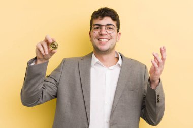 Genç yakışıklı adam kendini mutlu hissediyor, bir çözüm ya da fikir bulduğuna şaşırıyor. Bitcoin konsepti