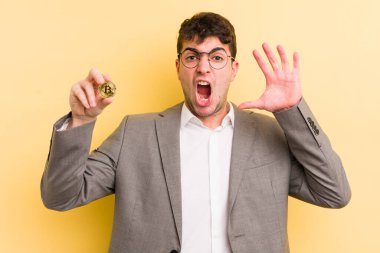 Genç yakışıklı adam ellerini havaya kaldırarak çığlık atıyor. Bitcoin konsepti