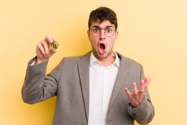 Genç ve yakışıklı bir adam şok olmuş ve şaşırmış hissediyor. Bitcoin konsepti