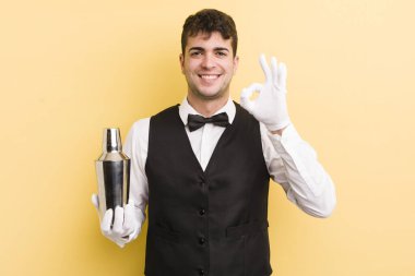 Genç yakışıklı adam kendini mutlu hissediyor, iyi bir jestle onaylıyor. barmen kokteyli
