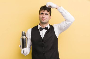 Genç yakışıklı adam mutlu bir şekilde gülümsüyor ve hayal kuruyor ya da şüphe ediyor. barmen kokteyli