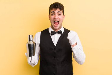 Genç yakışıklı adam şok olmuş hissediyor, gülüyor ve başarıyı kutluyor. barmen kokteyli