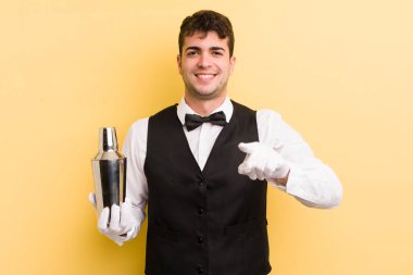 Genç ve yakışıklı bir adam kamerayı işaret ederek seni seçiyor. barmen kokteyli