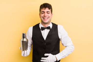 Genç yakışıklı bir adam komik bir şakaya yüksek sesle gülüyor. barmen kokteyli