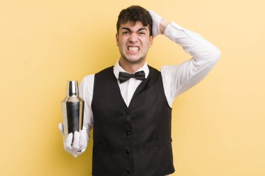 Genç ve yakışıklı bir adam stresli, endişeli ya da korkmuş hissediyor. Elleri başının üstünde. barmen kokteyli