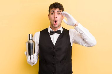 Genç yakışıklı adam mutlu, şaşkın ve şaşırmış görünüyor. barmen kokteyli