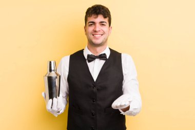 Genç ve yakışıklı bir adam arkadaşça gülümsüyor ve bir konsept sunuyor. barmen kokteyli