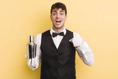 Genç ve yakışıklı bir adam mutlu hissediyor ve heyecanla kendini işaret ediyor. barmen kokteyli