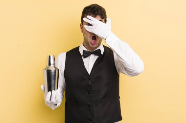 Genç, yakışıklı adam şok olmuş, korkmuş ya da korkmuş görünüyor. barmen kokteyli