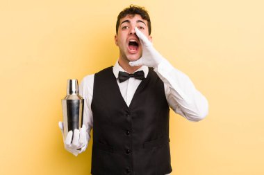 Genç yakışıklı adam mutlu hissediyor, elleri ağzının kenarında bağırıyor. barmen kokteyli