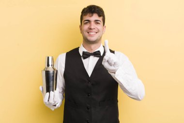 Genç yakışıklı adam gururla gülümsüyor ve kendinden emin bir numara oluyor. barmen kokteyli