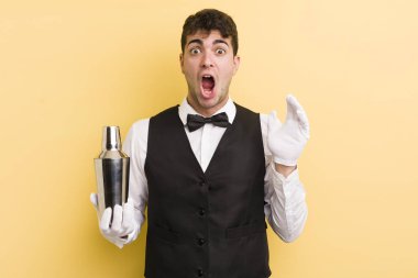 Genç yakışıklı adam kendini mutlu hissediyor ve inanılmaz bir şeye hayret ediyor. barmen kokteyli