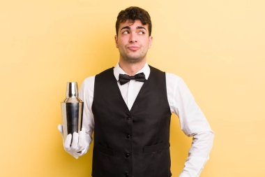 Genç yakışıklı adam omuz silkiyor, kafası karışık ve kararsız. barmen kokteyli