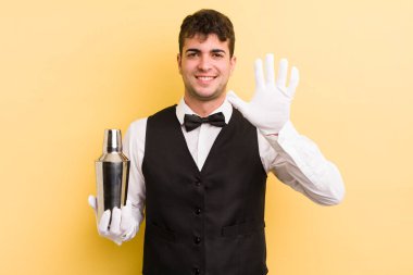 Genç yakışıklı adam gülümsüyor ve arkadaş canlısı görünüyor, beş numarayı gösteriyor. barmen kokteyli