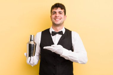 Genç yakışıklı adam neşeyle gülümsüyor, mutlu hissediyor ve bir konsept gösteriyor. barmen kokteyli