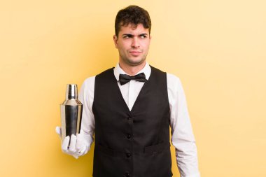 Genç ve yakışıklı bir adam üzgün, üzgün ya da kızgın hissediyor ve yan tarafa bakıyor. barmen kokteyli