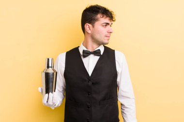 Profilde genç yakışıklı bir adam hayal kuruyor, hayal kuruyor ya da hayal kuruyor. barmen kokteyli