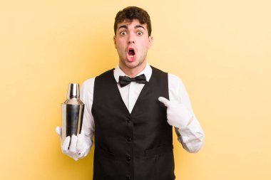Şok olmuş ve ağzı açık, kendini işaret eden genç ve yakışıklı bir adam. barmen kokteyli