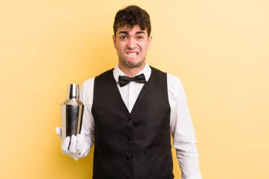 Kafası karışmış ve kafası karışmış genç yakışıklı bir adam. barmen kokteyli
