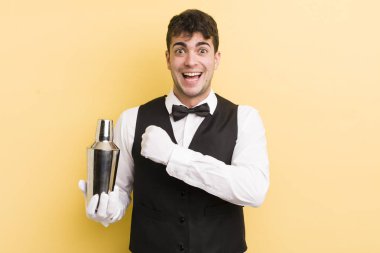 Genç yakışıklı adam kendini mutlu hissediyor ve bir meydan okumayla yüzleşiyor ya da kutluyor. barmen kokteyli