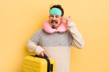 Genç yakışıklı adam mutsuz ve stresli görünüyor, intihar jesti silah işareti yapıyor. seyahat yolcu kavramı