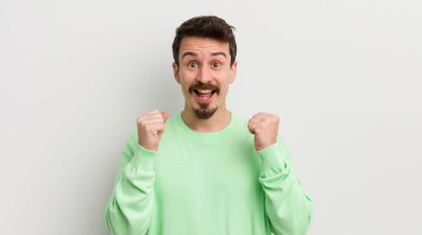 Genç yakışıklı adam şokta, gülüyor ve başarıyı kutluyor.