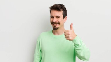 Genç yakışıklı adam gururlu, olumlu gülümsüyor.