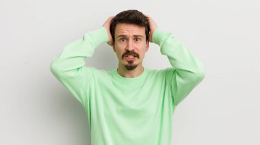Genç ve yakışıklı adam stresli, endişeli ya da korkmuş, elleri başının üstünde.