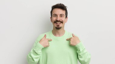 Genç yakışıklı adam mutlu hissediyor ve heyecanla kendini işaret ediyor.