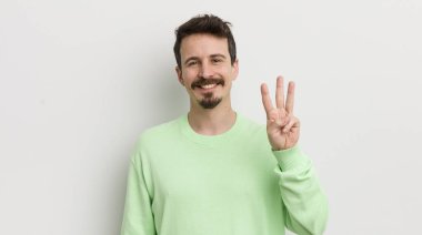 Genç yakışıklı adam gülümsüyor ve arkadaş canlısı görünüyor.